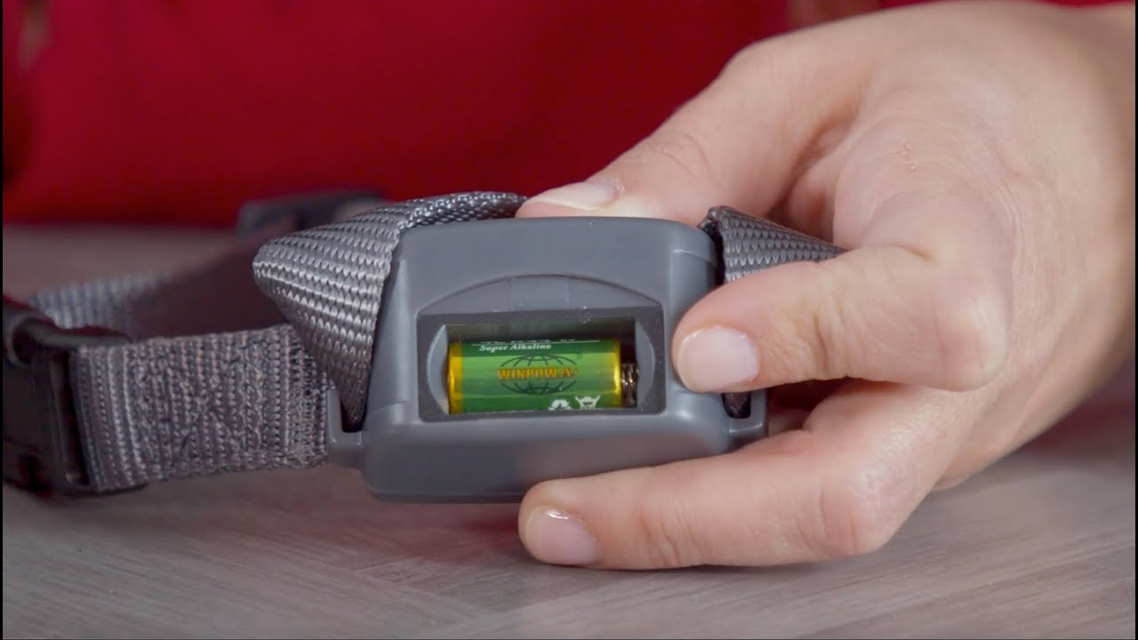 Hand installing a battery into a grey bark collar for your pet.