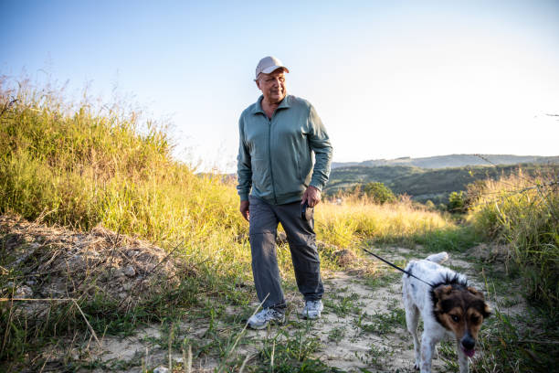 Older man walking his dog on a rural path. Use a bark collar for effective training.