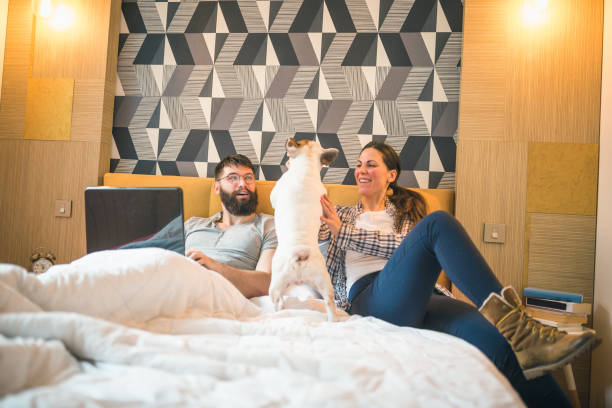 Couple relaxing in bed with their small dog, who might benefit from a quiet bark collar.