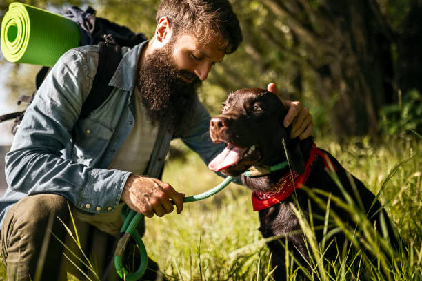 Hiker petting a happy brown dog on a leash, collar resembling a bark collar.